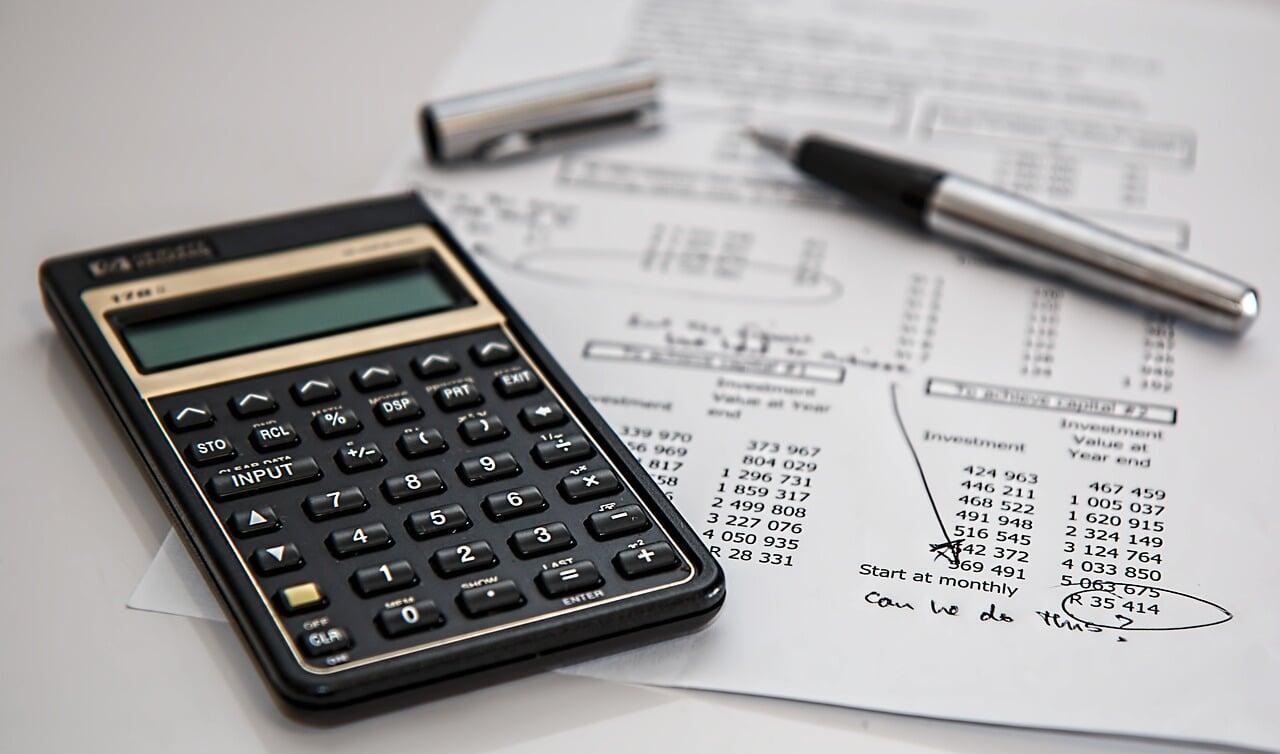 "Financial analysis with calculator, investment documents, and pen representing fractional CFO services for business cash flow management, financial strategy, and profitability optimization.